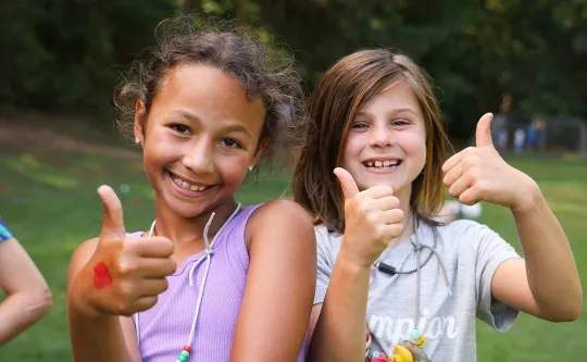 Two girls giving a thumbs-up at day camp