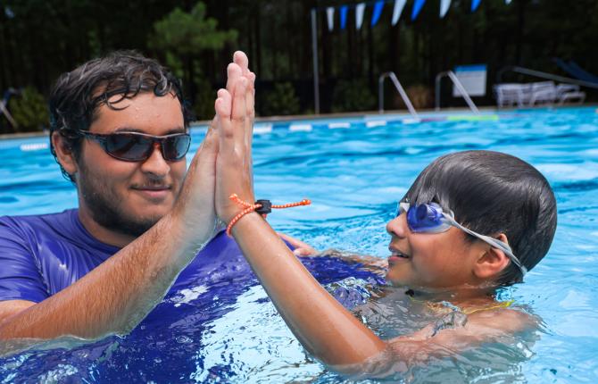 Instructor giving a child a high five during a swim lesson