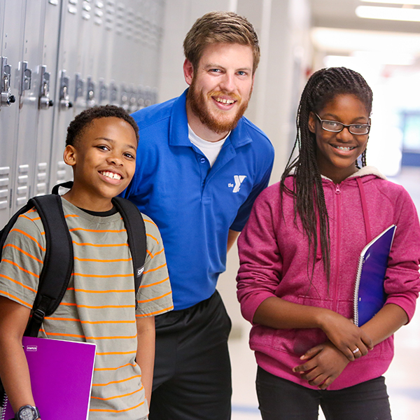 Counselor in school hallway talking to two students