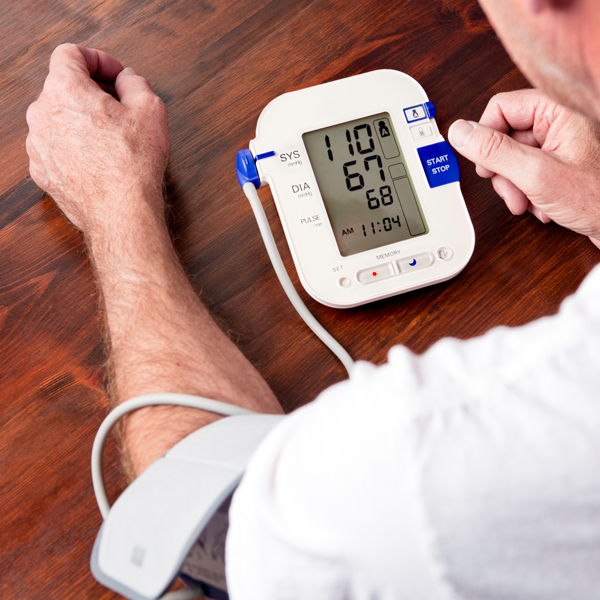 A man in a white shirt takes his blood pressure