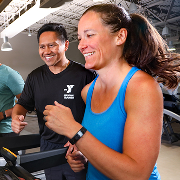 woman running on treadmill with coach