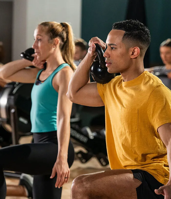Man and woman lifting kettle bells in a fitness class