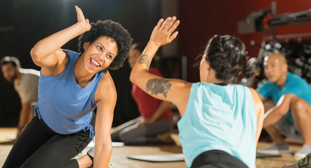 Two women in a group fitness class giving each other a high five.