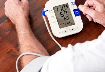 A man in a white shirt takes his blood pressure