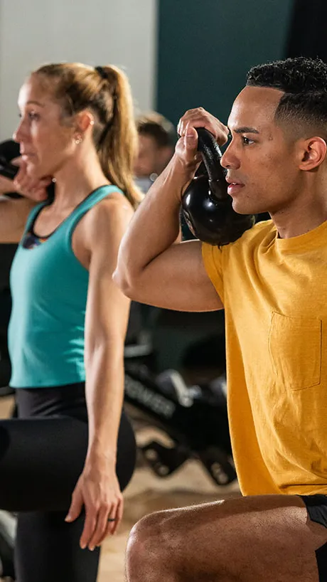 Man and woman lifting kettle bells in a fitness class