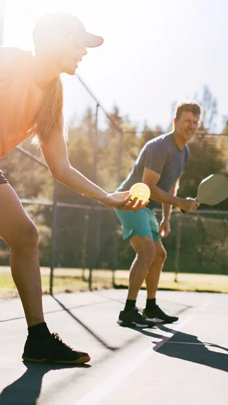 Man and woman playing doubles pickleball outside