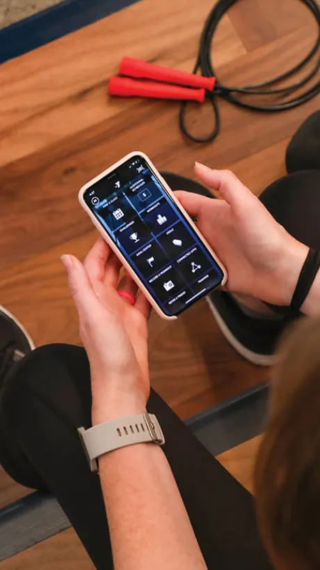 YMCA member holding a cell phone ready to use the new Member Pathways in the YMCA Fitness App
