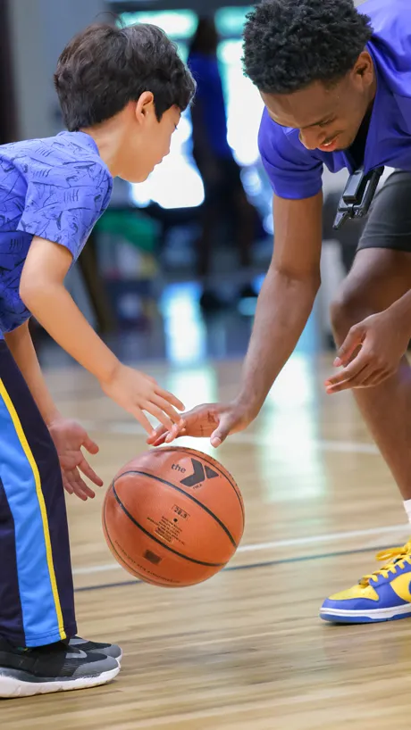 Counselor showing a boy basketball basic skills