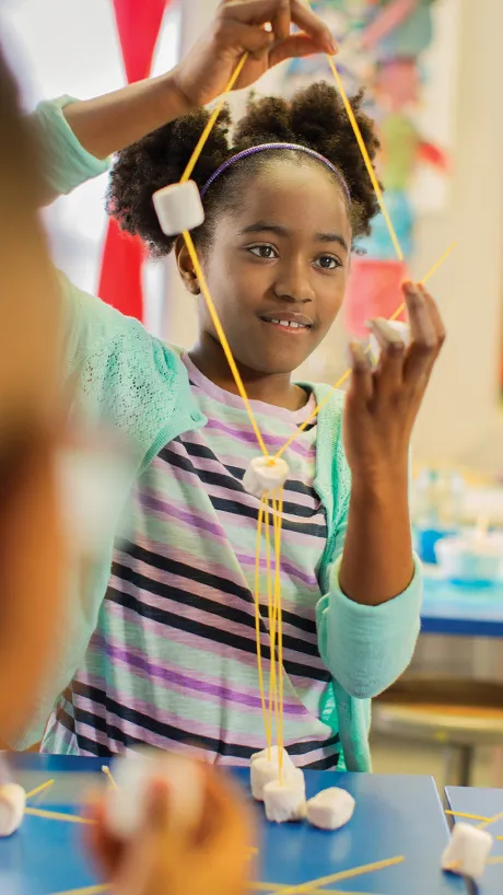Girl working on a fun activity with yarn and marshmallows