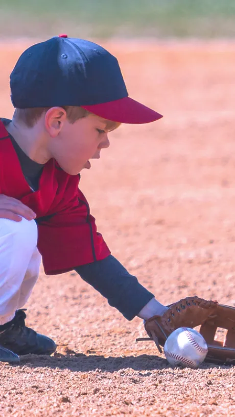 Child catching a ground ball in T-ball