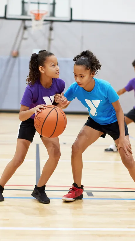 Two girls playing defense in youth basketball
