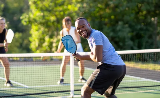 a man laughing as he plays pickleball
