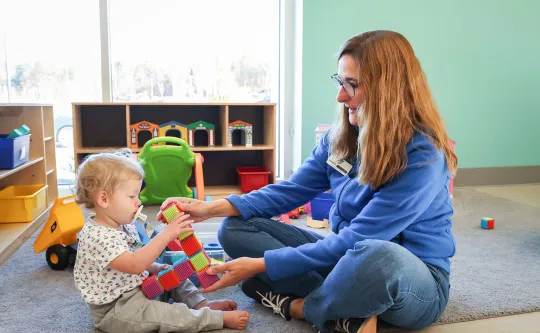 Child and staff member in the Kid Zone playing with blocks