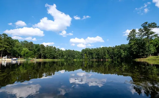 The lake at YMCA Camp Kanata, mirror still, reflecting green pine trees on both sides