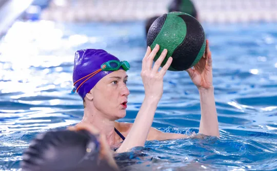 a member uses a strength ball in a water fitness class