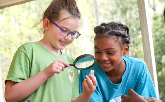 Two girls looking at a fossil with a magnifying glass