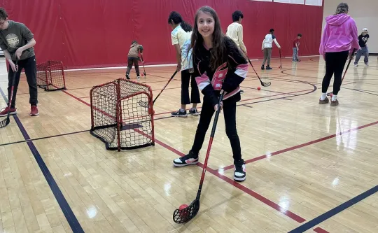 a young girl plays steet hockey at the YMCA