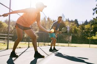 Man and woman playing doubles pickleball outside