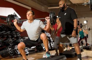 an instructor spots a member lifting a barbell
