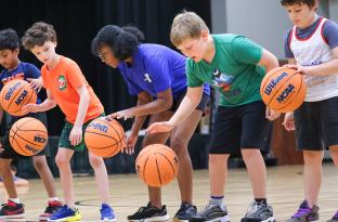 Group of kids learning dribble skills for basketball
