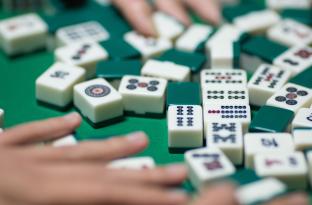 Hands moving game pieces around on a Mahjong table