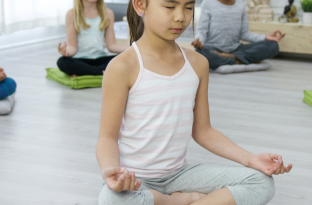 Children sitting on mat and floor in a seated yoga meditation position