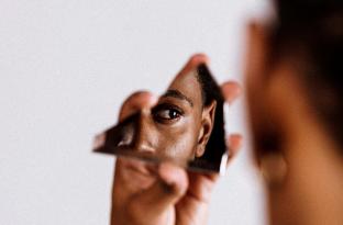 woman looking at herself through glass