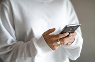 adult holding cell phone in the palm of hand