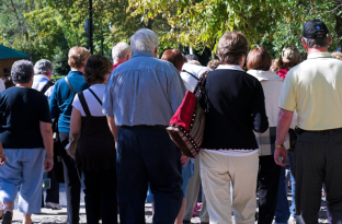 senior citizens on an outside tour walking with their backs turned
