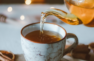 Porcelain tea cup on a table of white linen with twinkling lights in the background