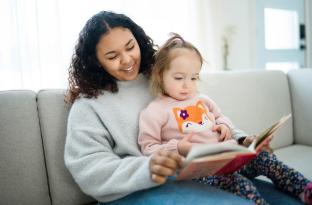a teenage babysitter reads to a young child