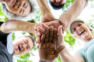 Image of active older adults smiling with hands in a circle