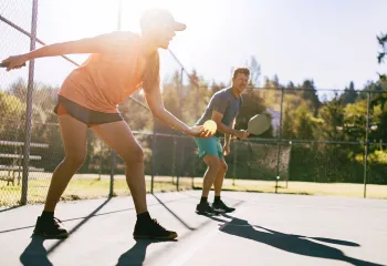 Man and woman playing doubles pickleball outside