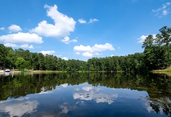 The lake at YMCA Camp Kanata, mirror still, reflecting green pine trees on both sides