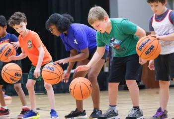 Group of kids learning dribble skills for basketball