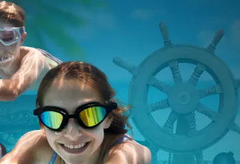Family swimming with pirate gear around them underwater with goggles