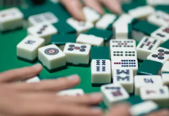 Hands moving game pieces around on a Mahjong table