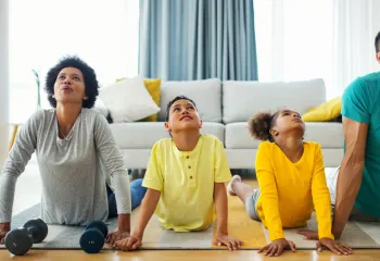 Family doing yoga- like stretches together in a bright airy room
