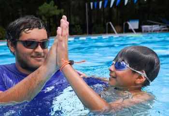 Instructor giving a child a high five during a swim lesson