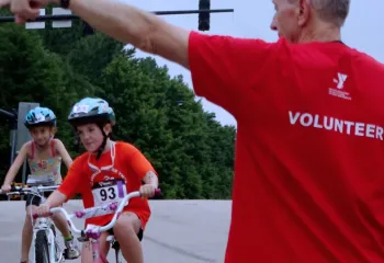 Adult Volunteer directing youth participants in a triathlon