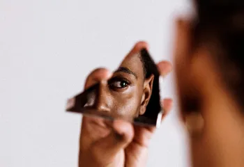 woman looking at herself through glass