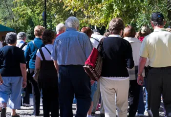 senior citizens on an outside tour walking with their backs turned