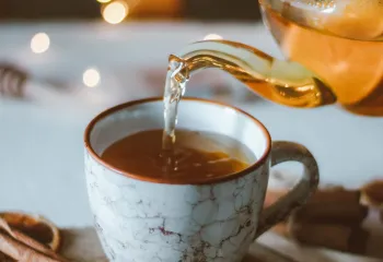 Porcelain tea cup on a table of white linen with twinkling lights in the background