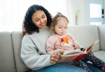 a teenage babysitter reads to a young child