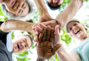 Image of active older adults smiling with hands in a circle