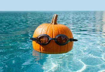 Pumpkin in swim goggles in pool water