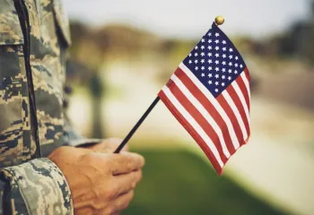 uniformed Military personnel holding a small American flag