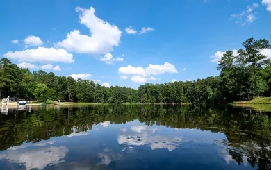 The lake at YMCA Camp Kanata, mirror still, reflecting green pine trees on both sides