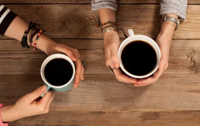 hands holding coffee cups at a table