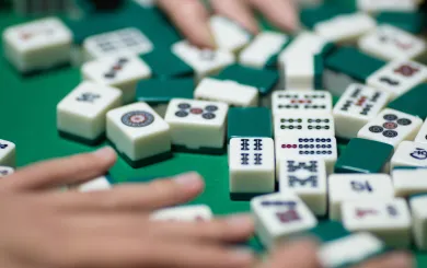 Hands moving game pieces around on a Mahjong table